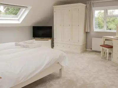 a white bedroom with a bed and a tv at The Big Dingle in Church Stretton