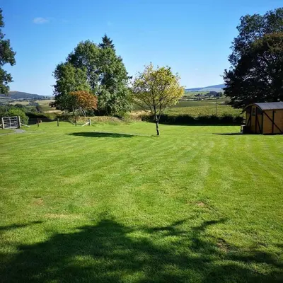a large grassy field with trees in the background at the cwch in Llanbister