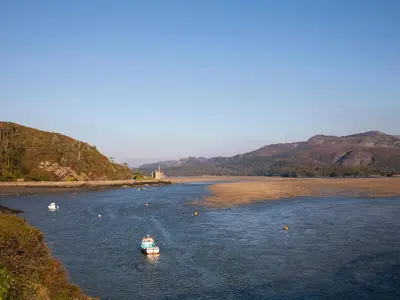 two boats in a river with mountains in the background at Glan Meon Cottage in Barmouth