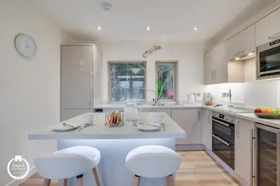 a kitchen with white cabinets and a island with stools at The Old Stables Aberdyfi apartment 3 in Aberdyfi