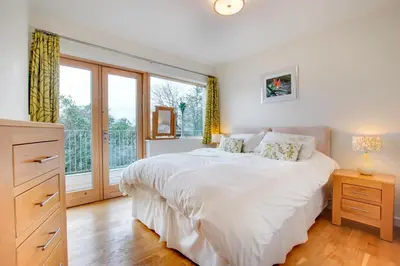a bedroom with a white bed and a large window at The Old Stables Aberdyfi apartment 6 in Aberdyfi