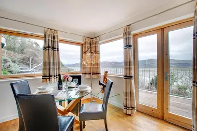 a dining room with a table and chairs and large windows at The Old Stables Aberdyfi apartment 6 in Aberdyfi