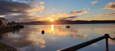 a sunset on a river with a boat in the water at The Old Stables Aberdyfi apartment 6 in Aberdyfi
