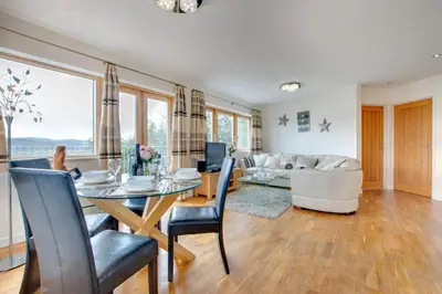 a dining room and living room with a table and chairs at The Old Stables Aberdyfi apartment 6 in Aberdyfi