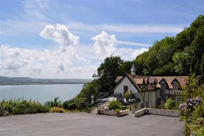 a house on a hill next to a body of water at The Old Stables Aberdyfi apartment 6 in Aberdyfi