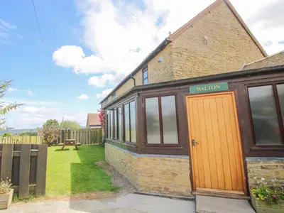 a brick house with a yellow door in a yard at The Walton in Craven Arms