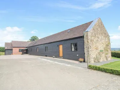 a barn with a stone building with a driveway at The Park in Craven Arms