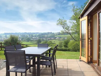 a table and chairs on a patio with a view at Talog Barn-Uk31366 in Tregynon