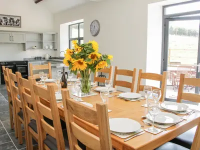 a dining room table with a vase of yellow flowers at The Farm in Presteigne