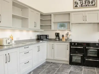 a kitchen with white cabinets and black appliances at The Farm in Presteigne