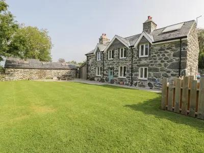 an old stone house with a lawn in front of it at Tyn Ffynnon in Dyffryn