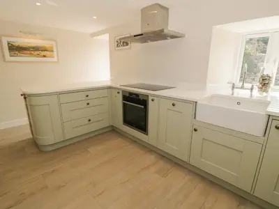 a white kitchen with white cabinets and a sink at Tyn Ffynnon in Dyffryn