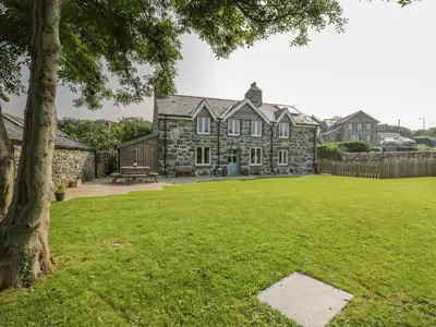 an old stone house with a grass yard at Tyn Ffynnon in Dyffryn