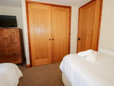 a bedroom with two beds and a wooden door at Norton Cottage in Craven Arms