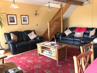 a living room with a black leather couch and a table at Peacock Cottage, Coity Bach in Talybont