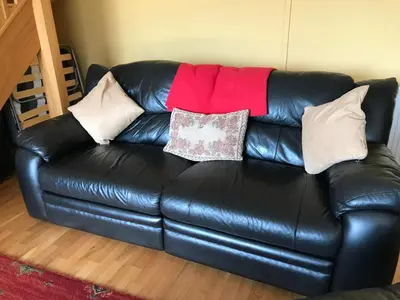 a black leather couch with pillows on it at Peacock Cottage, Coity Bach in Talybont