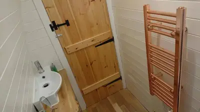 a small bathroom with a sink and a wooden door at Owl Hut Cosy Ensuite Pod Snowdonia Coast Sleeps 2 in Dolgellau