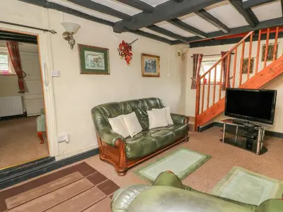 a living room with a leather couch and a flat screen tv at Caerau Farm House in Llanidloes