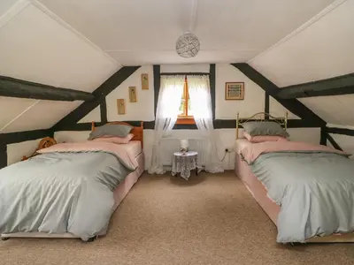 two beds in a attic room with a window at Caerau Farm House in Llanidloes