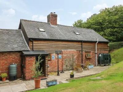 a brick house with a patio in front of it at Caerau Farm House in Llanidloes