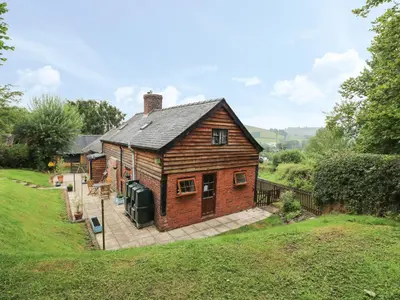 a small house with a large patio in a yard at Caerau Farm House in Llanidloes