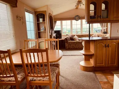 a kitchen and living room with a table and chairs at 157 Amour Caravan in Tywyn