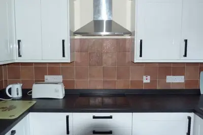 a kitchen with white cabinets and a stove at Willow Cottage in North Lydbury