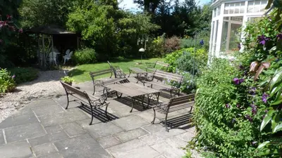 a group of benches and a table in a garden at Willow Cottage in North Lydbury