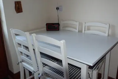 a white dining room table with four white chairs at Willow Cottage in North Lydbury