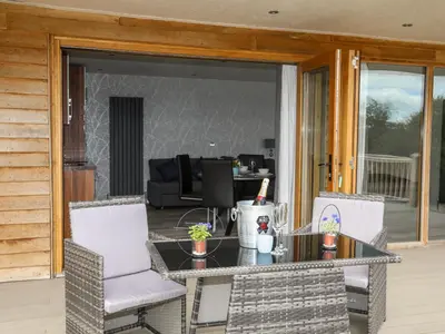 a patio with a table and chairs on a porch at Meadow Lodge in Corwen