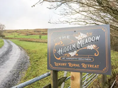 a sign for the hidden meadow at a country road at Meadow Lodge in Corwen