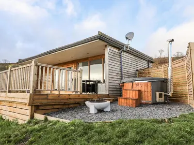 a small house with a deck and a tub at Meadow Lodge in Corwen