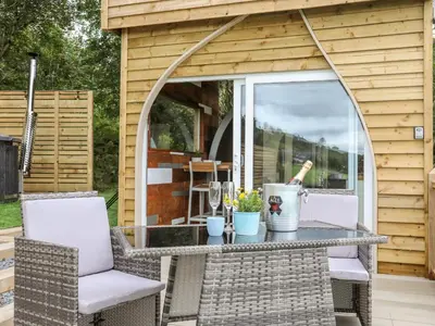 a screened in porch with a table and chairs at Woodland Pod in Corwen