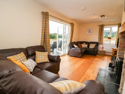 a living room with a leather couch and a fireplace at Lower Pentre in Llandrindod Wells
