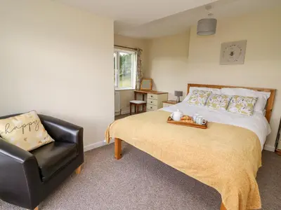 a bedroom with a bed and a black leather chair at Lower Pentre in Llandrindod Wells