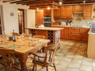 a kitchen with a wooden table with chairs and a counter at Bryn Celyn in Oswestry