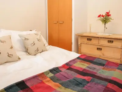 a bed with a multicolored blanket and a dresser at Bryn Celyn in Oswestry