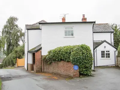 a white house with a brick wall at Bryn Celyn in Oswestry