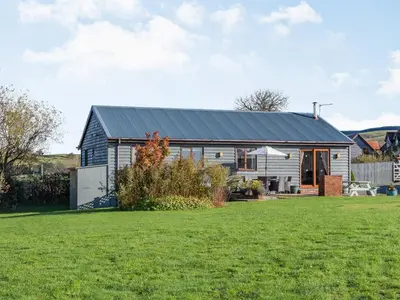 a house with a black roof and a yard at Cuckoo Hill Lodge in Saint Harmon