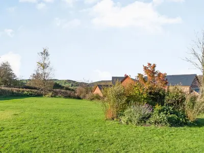 a field of grass with a house in the background at Cuckoo Hill Lodge in Saint Harmon