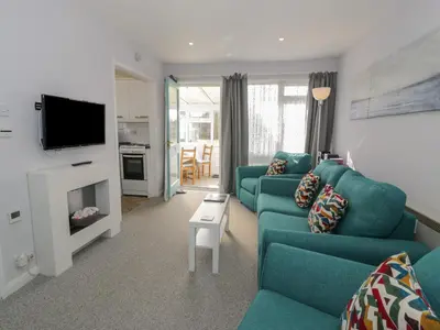 a living room with a blue couch and a tv at Hafod-y-Gors in Fairbourne
