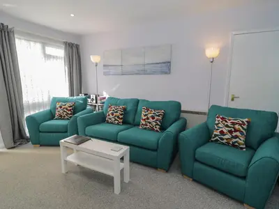 a living room with two blue chairs and a table at Hafod-y-Gors in Fairbourne