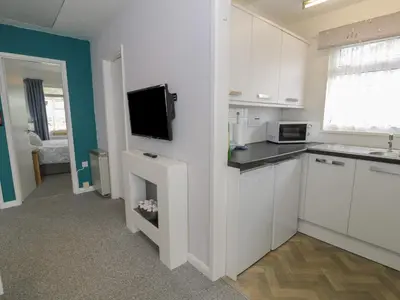 a kitchen with white cabinets and a flat screen tv at Hafod-y-Gors in Fairbourne