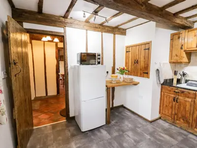 a kitchen with a white refrigerator and wooden cabinets at Wilstone Cottage in Church Stretton