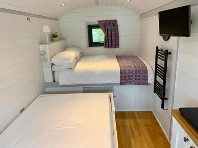 a small bedroom in a tiny house with a bed at Shepherds Hut at Wern Mill in New Quay