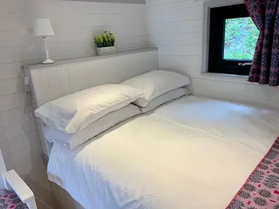 a bed with two pillows in a room with a window at Shepherds Hut at Wern Mill in New Quay