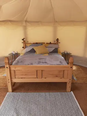 a bedroom with a wooden bed in a tent at Cae Mawr Yurt Off-Grid Glamping in Machynlleth