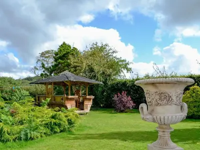 a garden with a gazebo and a vase in the grass at Tan y Gaer in Aberystwyth
