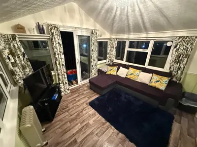 a living room with a couch and a television at Chalet 5 Clarach Bay in Aberystwyth