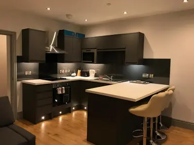 a kitchen with black cabinets and a white counter top at Belmont - Y Prom in Aberystwyth